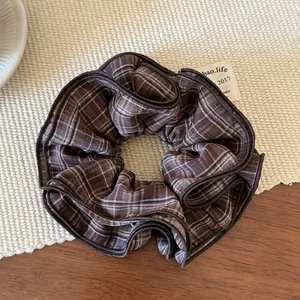 Macro shot of brown plaid oversized scrunchie with layered ruffles and neat hemmed edges