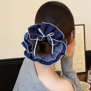 Large blue checkered scrunchie with white ribbon bow and pleated trim on a ponytail