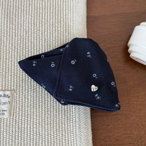 Close-up of dark blue floral hair claw clip featuring white prints and a silver heart charm