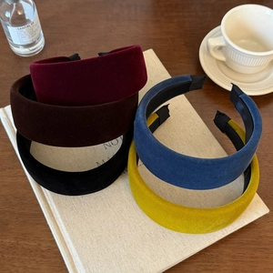 Detailed view of various velvet wide headbands stacked on books in a stylish setup