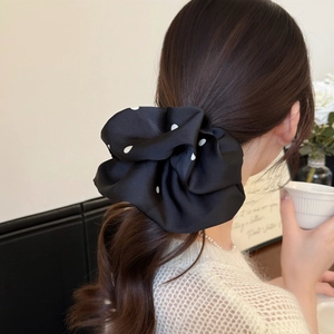 Gros plan d'un chouchou en satin à pois noir et blanc de style français sur cheveux