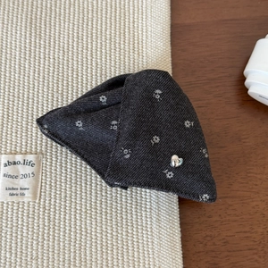 Detailed view of dark grey floral fabric hair claw with a small silver heart-shaped button