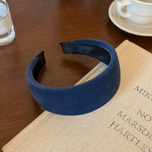 Detail of dark blue velvet wide headband on a vintage table with coffee cup and book