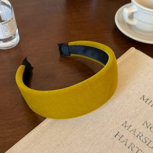 Close-up of mustard yellow velvet padded headband on a vintage book with warm cafe vibes