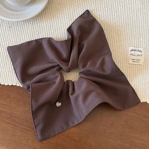 Close-up of brown striped scrunchie fabric with a small sparkling heart charm detail