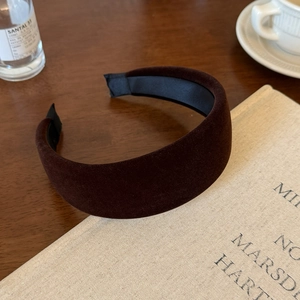 Detail of dark brown velvet wide headband with non-slip lining on a wooden desk