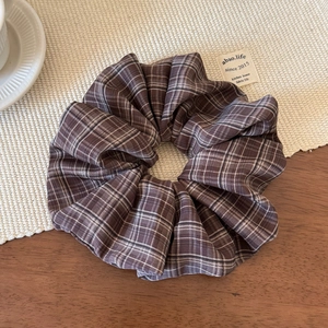 Detailed view of a vintage dark brown plaid scrunchie with rich fabric folds