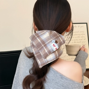 Brown and blue checkered fabric scrunchie with buttons and a white brand label