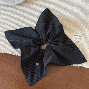 Detail of black and white striped scrunchie with a silver heart-shaped metal buckle