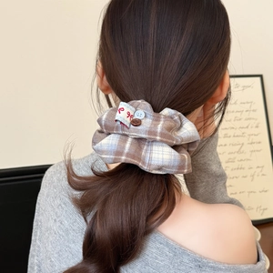 Detailed view of checkered plaid scrunchie with vintage buttons on a low ponytail hair
