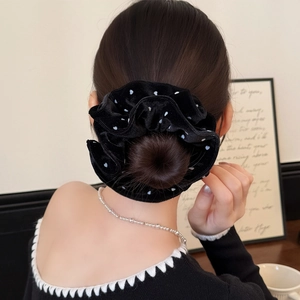 Close-up of a velvet polka dot hair scrunchie on a bun with elegant pearl necklace
