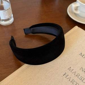 Detail view of a black velvet padded headband resting on a book in a cozy setting