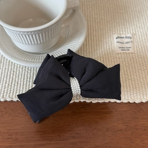 Détail d'une pince à cheveux en tissu noir avec des ornements de perles élégantes