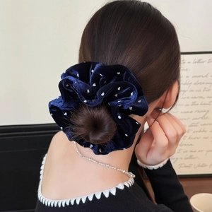 Close-up of a navy blue velvet polka dot scrunchie styled on a classic hair bun
