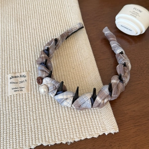 Detail showing the anti-slip black teeth and woven fabric texture of the plaid headband