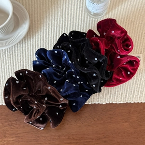 Detail of four velvet polka dot hair scrunchies in brown, navy, black, and wine red colors