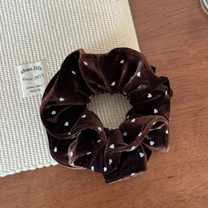 Detailed texture of coffee brown velvet scrunchie with white polka dots and elegant trim