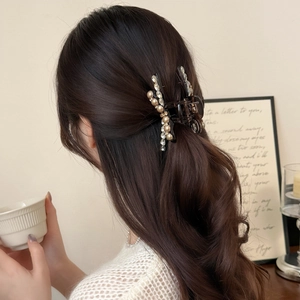 Elegante pinza para el cabello con cristales y perlas, mostrada en cabello castaño ondulado