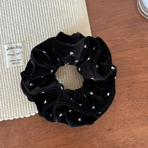 Close-up of velvet polka dot scrunchie on wooden table with elegant texture