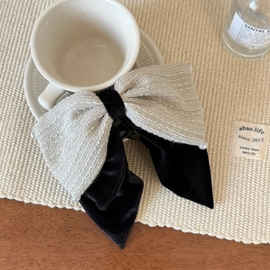Detail der Tweed-Haarschleife mit Perlenrand und schwarzem Samtband auf einem Tisch