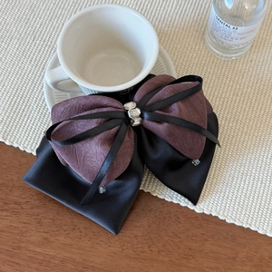 Detail of elegant two-tone satin bow hair claw clip with sparkling rhinestones decoration