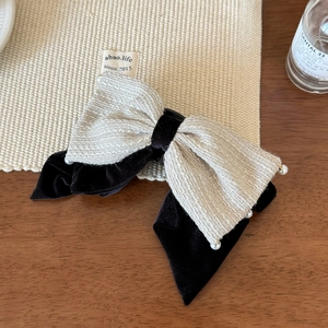 Detail einer Tweed- und Samt-Haarschleife mit weißen Perlen und edler Textur