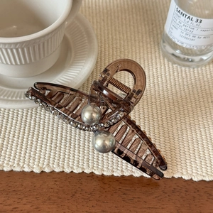 Braune Acryl Haarklammer mit Perlen und Strasssteinen auf einer weißen Strickmatte