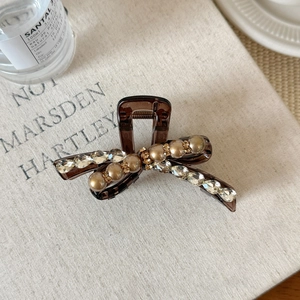 Detalle de pinza para el pelo de lujo con pedrería y perlas sobre base color ámbar