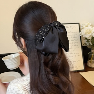 Eleganter schwarzer Pailletten-Schleifen-Haarclip für Damen auf langem gewelltem Haar