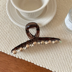 Haarklammer aus braunem Acryl mit Perlen und Strass auf beige strukturiertem Hintergrund