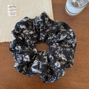 Detail of vintage ink marble fabric scrunchie with embroidered tag on wooden table