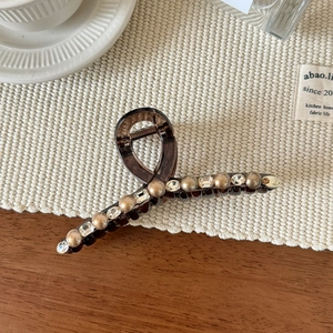 Detail der eleganten braunen Haarklammer mit Strasssteinen und Akzenten aus Kunstperlen