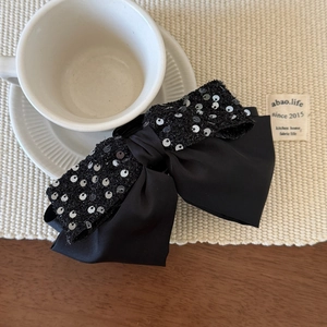 Eleganter schwarzer Pailletten Haarclip mit silbernem Glitzer auf Untertasse