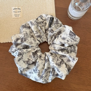 Detailed view of ink-wash marble scrunchie on wood with Blind for Love label