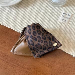 Vintage leopard print triangular hair claw clip with gold metallic detail on wood desk