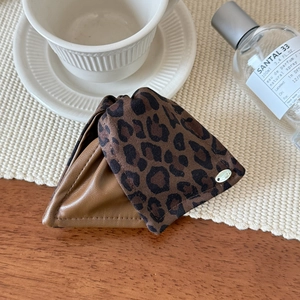 Close-up of leopard print fabric and brown leather detail with metal logo on hair claw