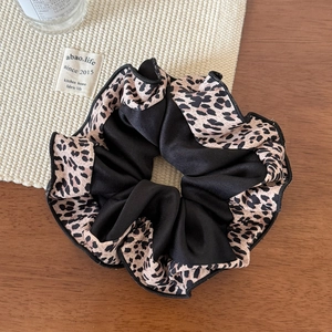 Close-up of leopard print and black fabric scrunchie with fine stitching details