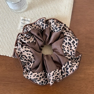 Close-up of leopard print satin scrunchie with elegant pleated fabric texture