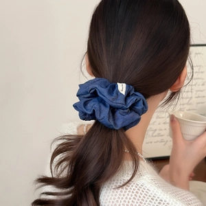 Blue denim oversized scrunchie with Hand Made label on a low ponytail hairstyle