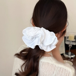Close-up of fluffy white ruffled scrunchie hair tie worn by model for elegant hairstyle