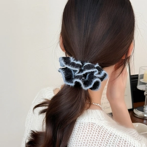 Handmade woven scrunchie in black and light blue fuzzy trim shown on model hair