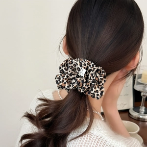 Elegant leopard print scrunchie hair tie styled with a white knit sweater and pearls