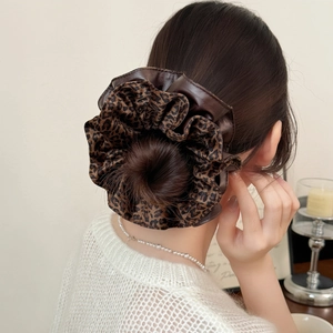 Vintage leopard print and brown faux leather scrunchie on a bun hairstyle