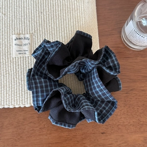 Détail d'un chouchou en tissu à carreaux bleu et noir sur fond en tricot doux