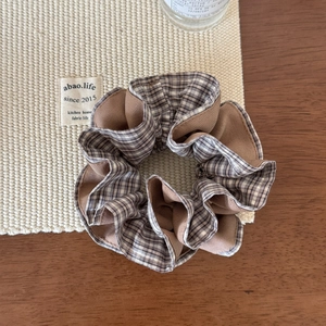 Détail d'un chouchou en tissu à carreaux avec texture superposée sur bois chaleureux