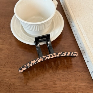 Detail of a French vintage leopard print hair claw clip on a dark wood background