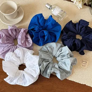 Five assorted oversized ruffled fabric hair scrunchies in minimalist pastel colors