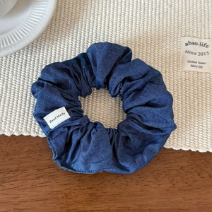 Close-up of denim fabric scrunchie with handmade label on a rustic wooden table