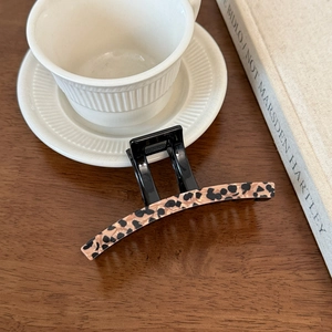 Detailed close-up of French leopard print acetate hair claw clip on a rustic wooden table