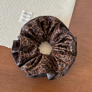 Close-up of leopard print fabric and brown faux leather patchwork on a scrunchie